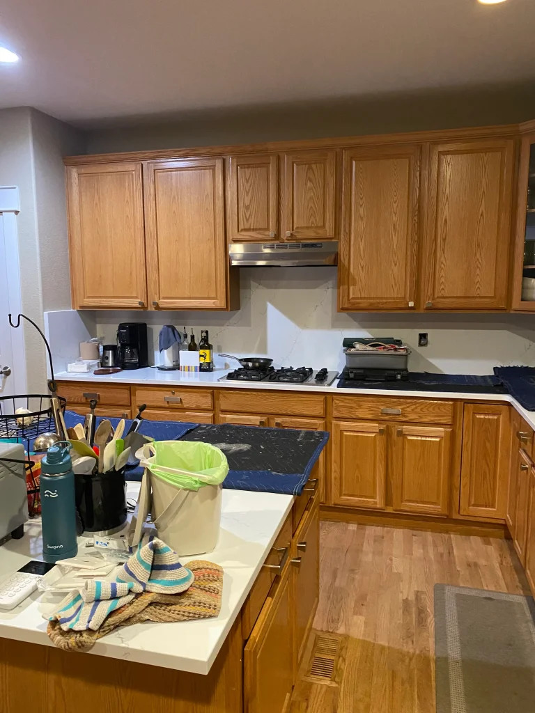 Before cabinet refacing showing oak cabinets around built-in oven and refrigerator in Denver home